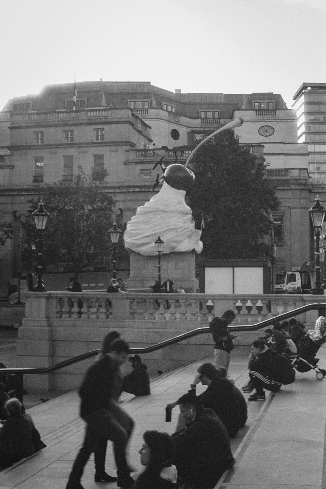 Black and white street scene with a crowd gathered near a building
