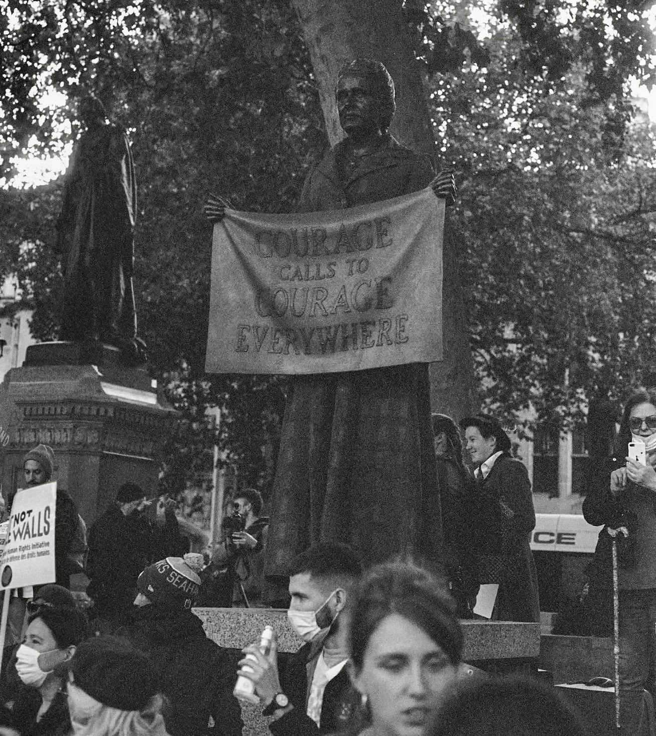 Black and white documentary photograph of a street demonstration with a banner