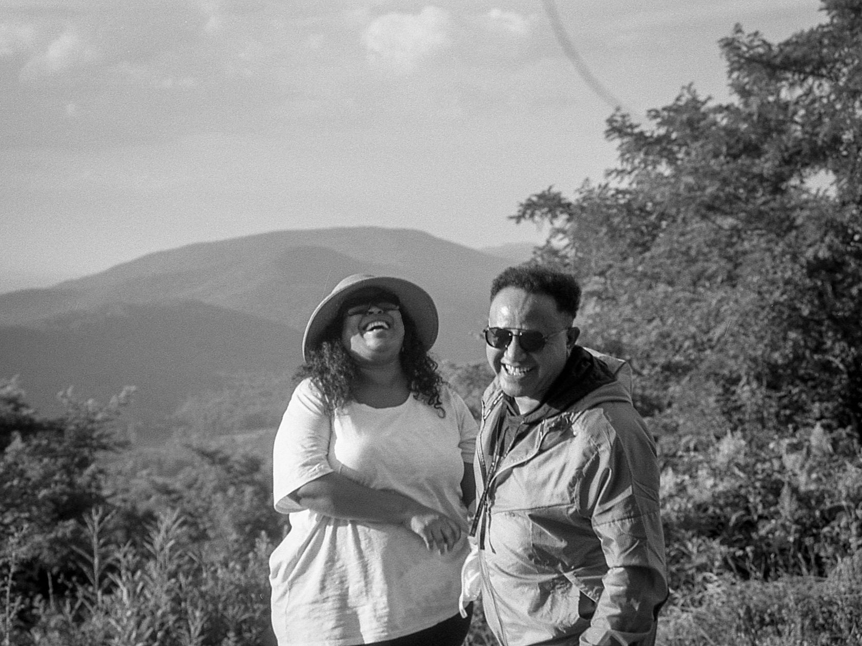 Black and white photograph of two people standing on a hillside