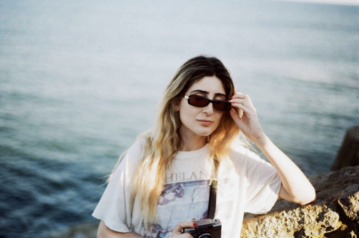 A woman wearing sunglasses standing by the water