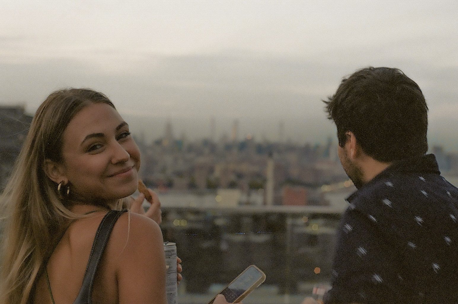 A woman looking back over her shoulder with a city skyline behind her